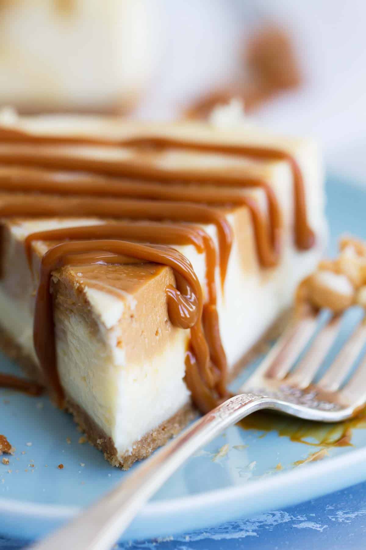 Slice of Dulce de Leche Cheesecake with caramel drizzled over the top