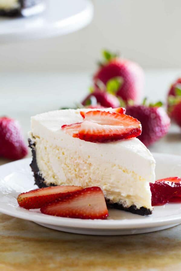 slice of Sour Cream Cheesecake topped with fresh strawberries.