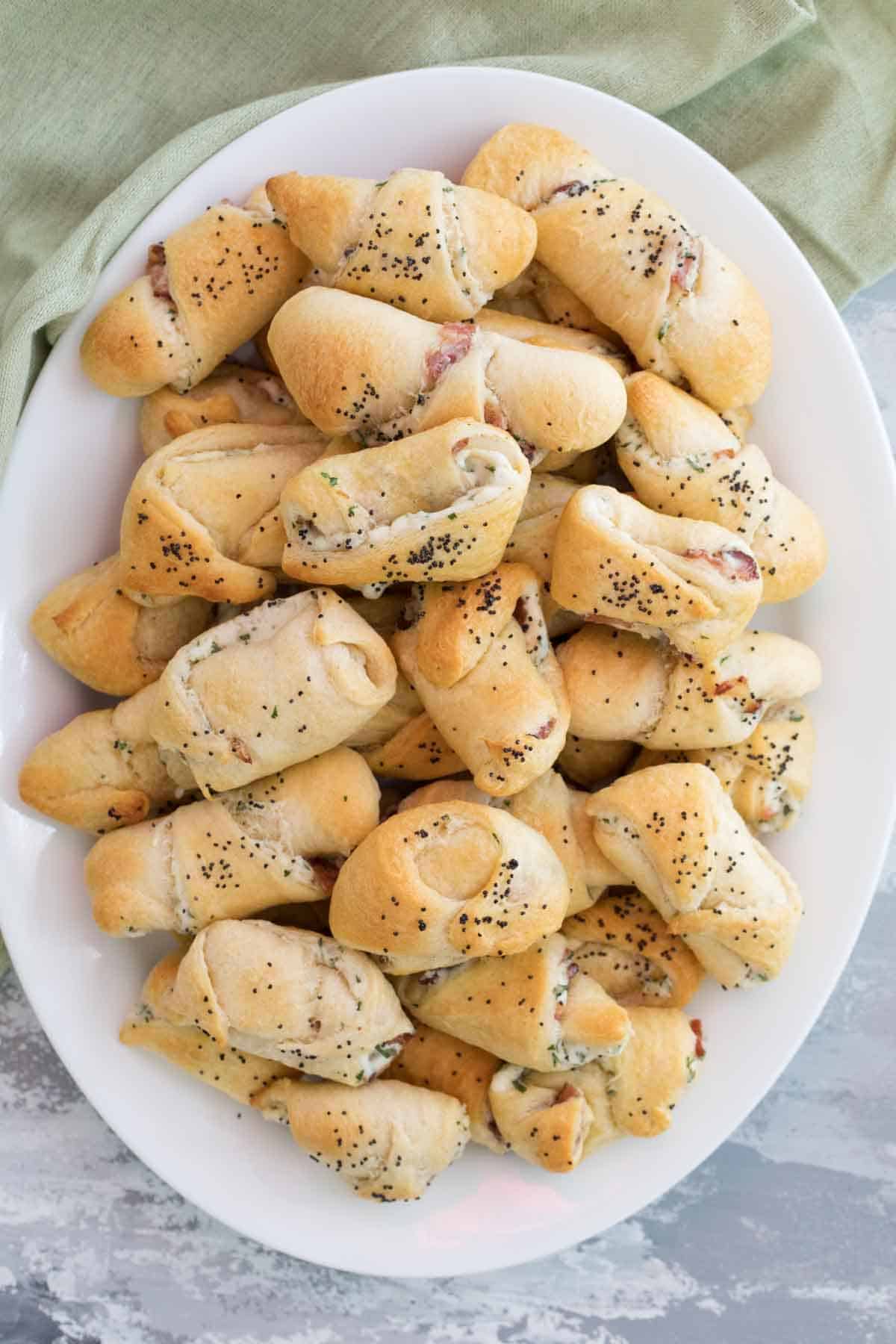 Plate filled with appetizers made from crescent rolls filled with bacon and cream cheese.