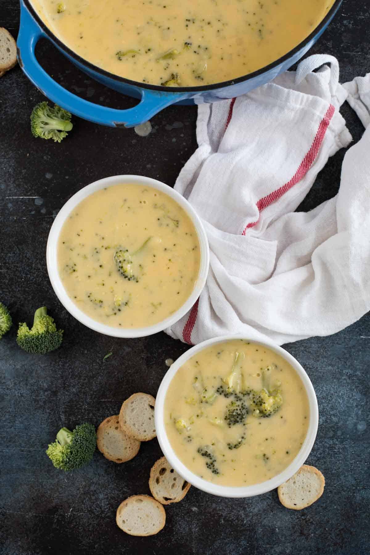 overhead view of two bowls of broccoli cheese soup