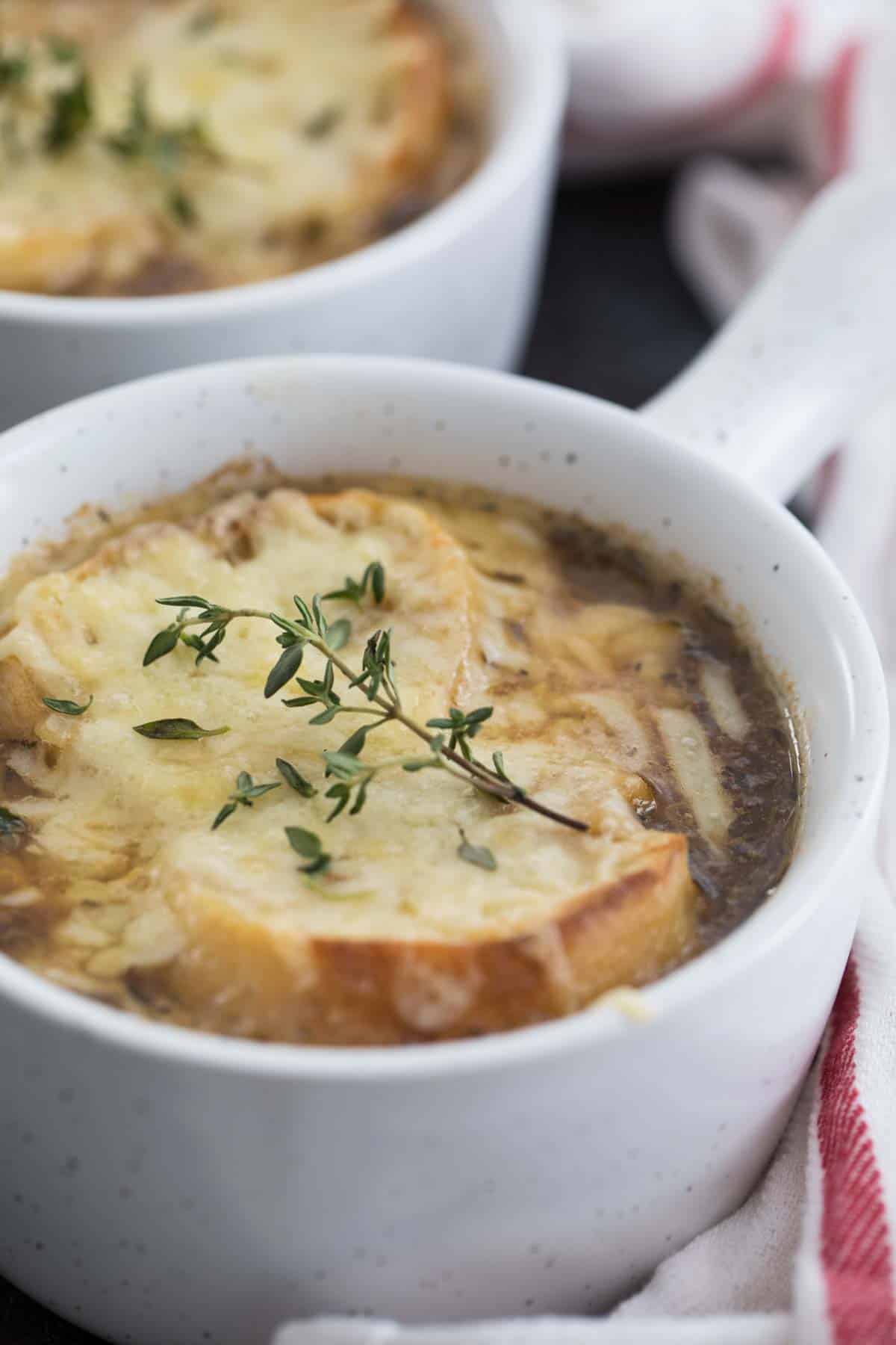 close up of French onion soup topped with cheese and thyme