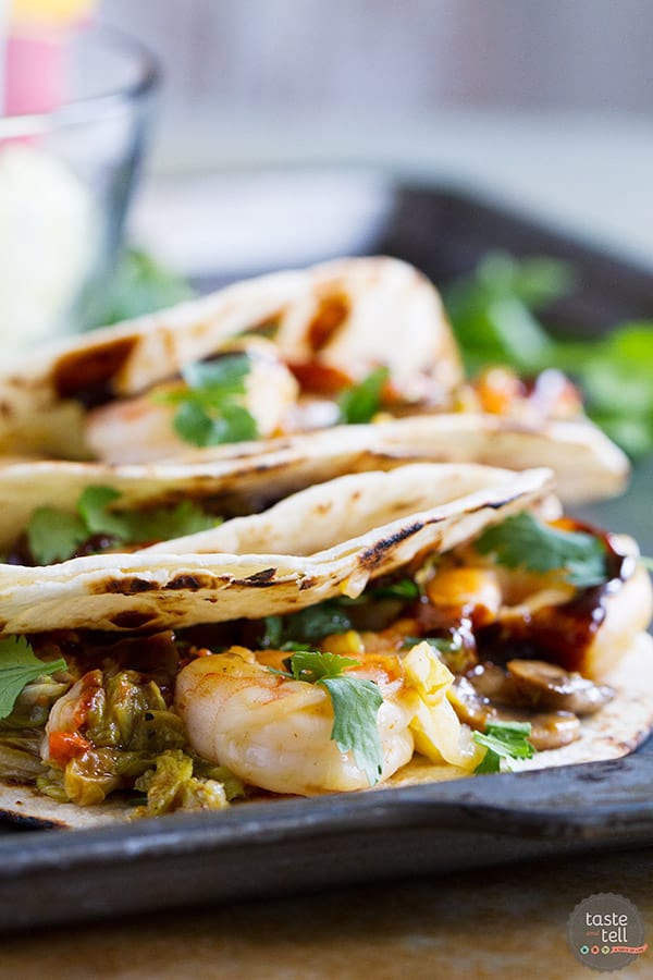 Tacos go Asian in this easy weeknight meal. These Moo Shu Shrimp tacos have shrimp combined with mushrooms, carrots, green onions and cabbage and a simple sauce. The mixture is served in tortillas, topped with hoisin sauce and cilantro.