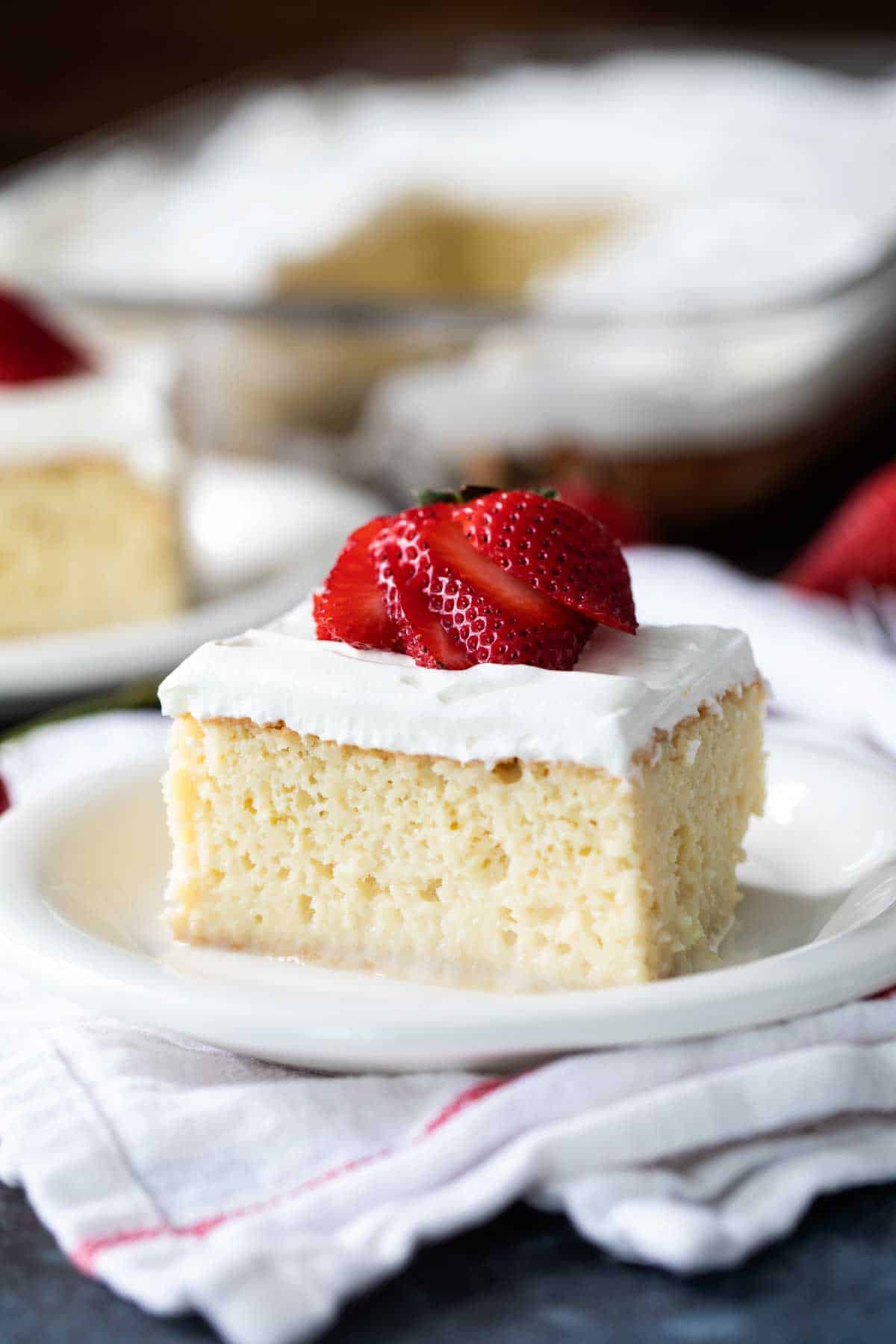 slice of Homemade Tres Leches Cake topped with a fresh strawberry