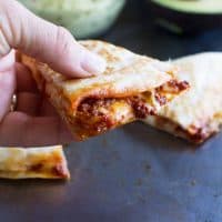 Hand holding a section of a shrimp quesadilla with chorizo.