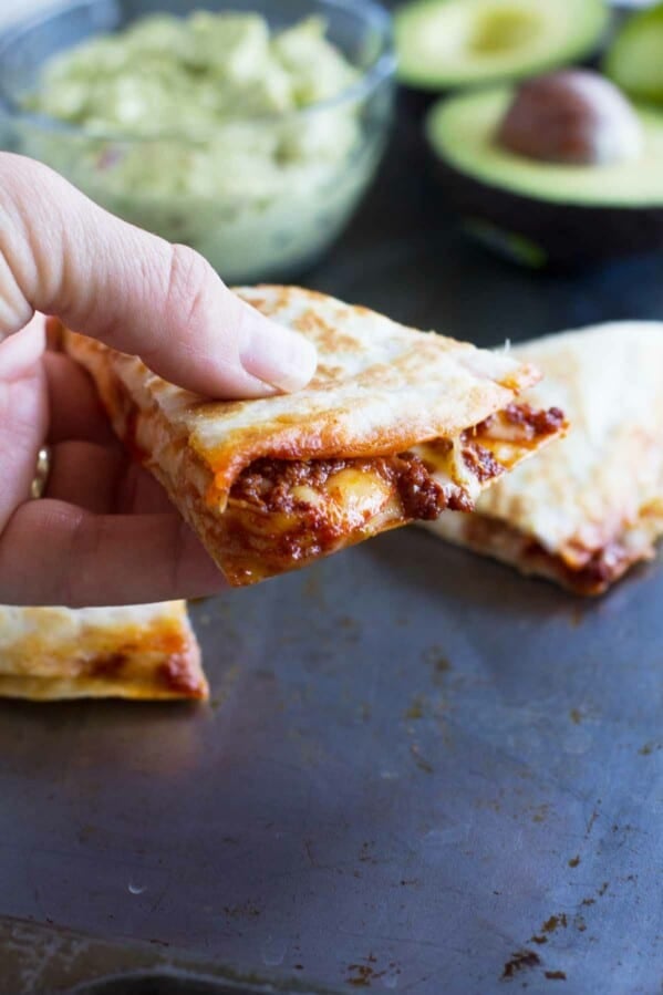 Hand holding a section of a shrimp quesadilla with chorizo.