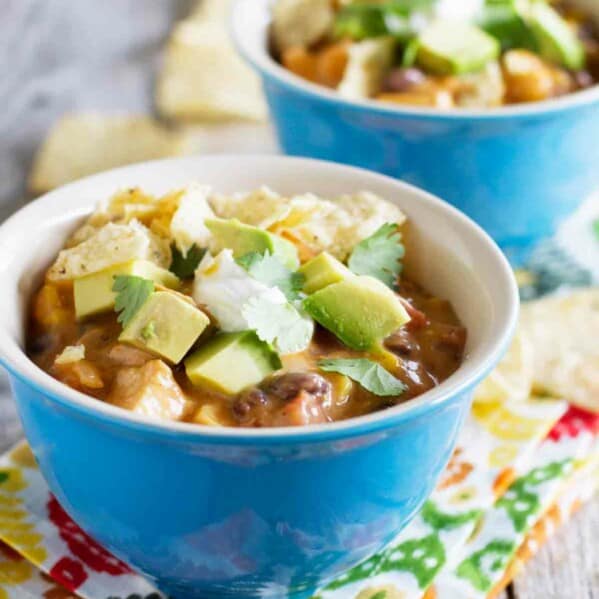 two bowls with chicken soup topped with avocados