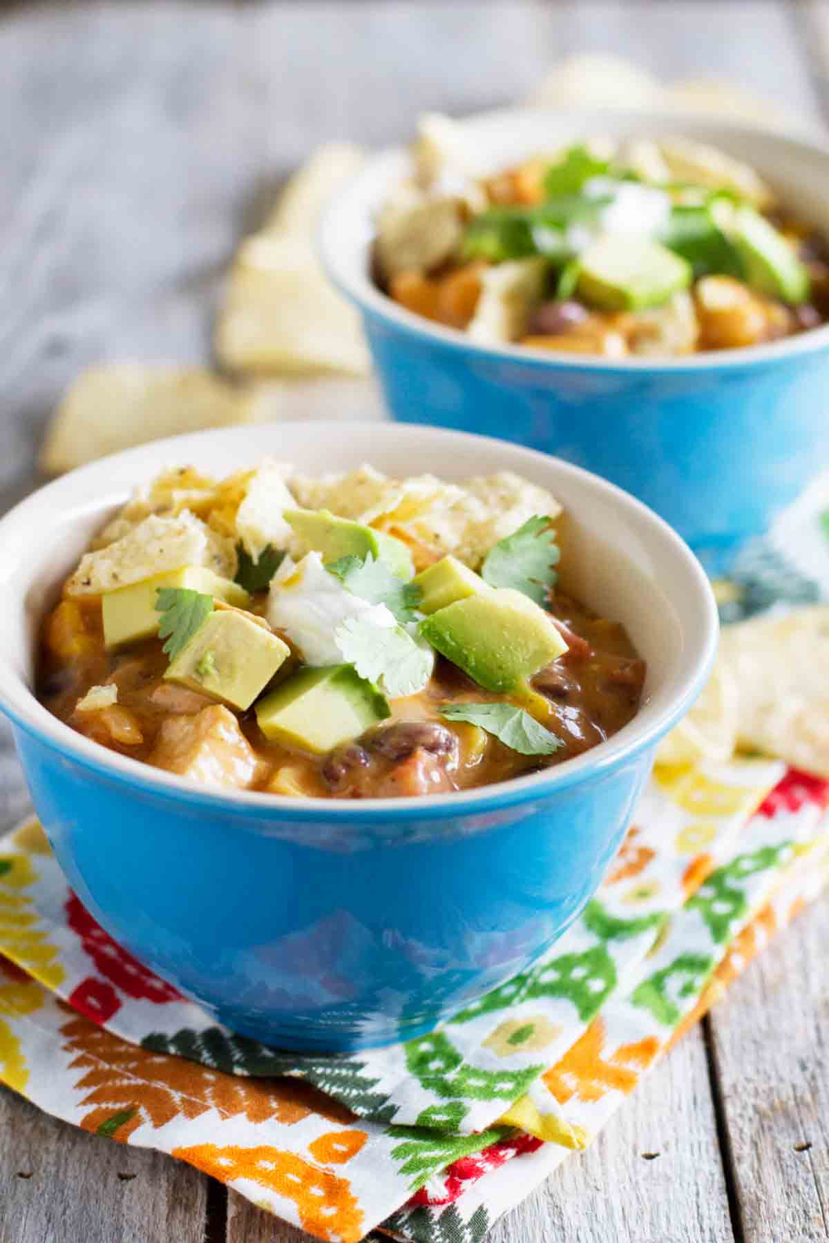 two bowls with chicken soup topped with avocados