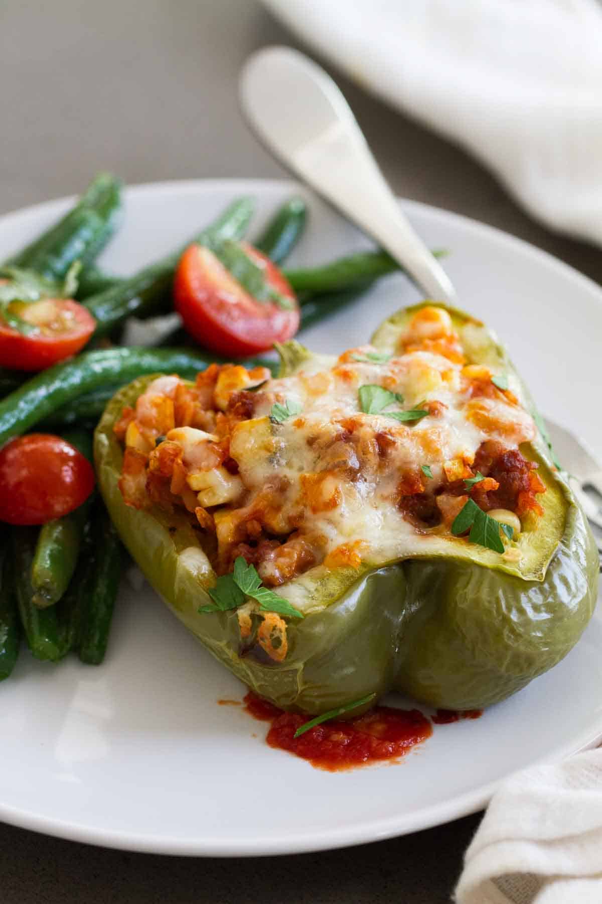 The perfect way to get in your veggies, these Vegetable and Sausage Stuffed Peppers are stuffed with lots of veggies, rice and flavorful sausage. The perfect end of summer meal! Bell pepper cut in half and stuffed with vegetables and sausage
