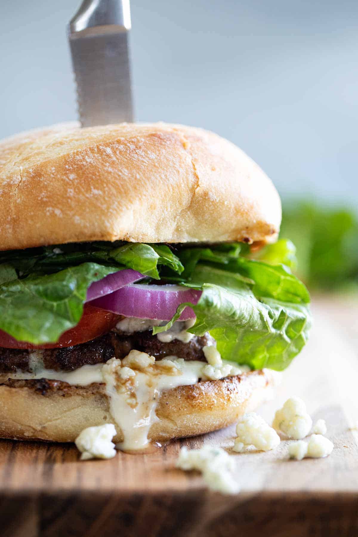 close up of blue cheese burger with a steak knife through it