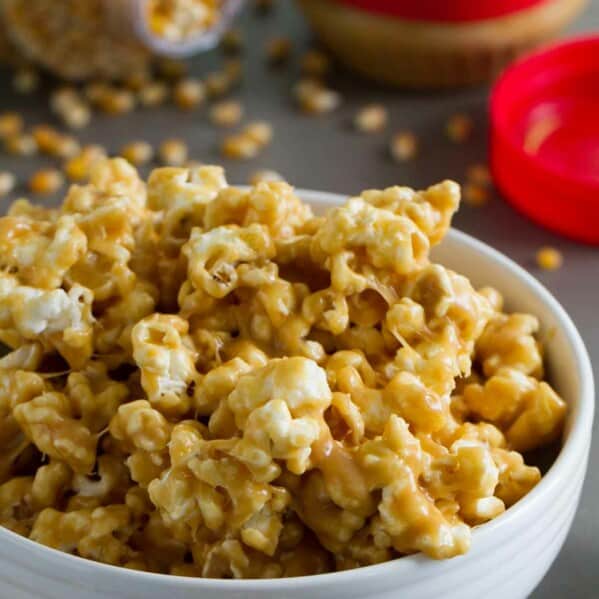 Bowl of peanut butter popcorn with more popcorn in the background.