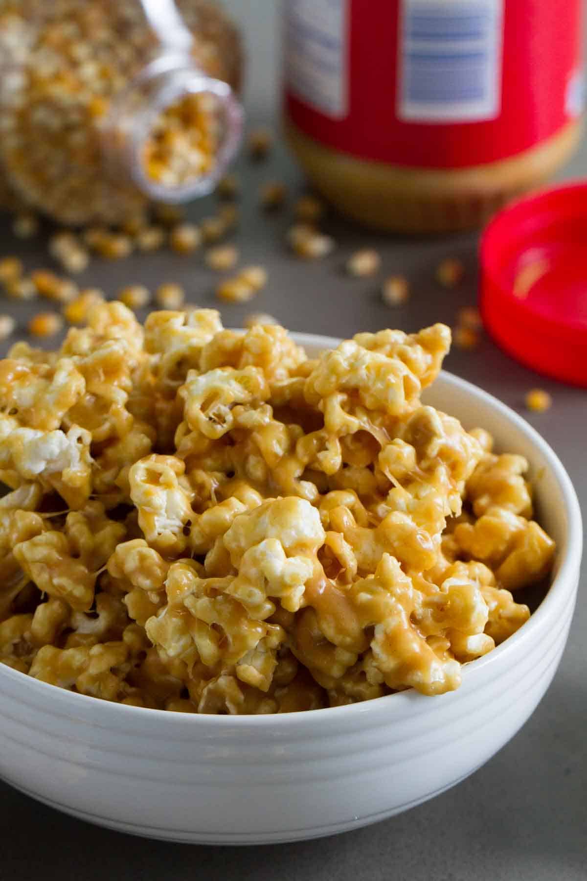 Bowl of peanut butter popcorn with more popcorn in the background.