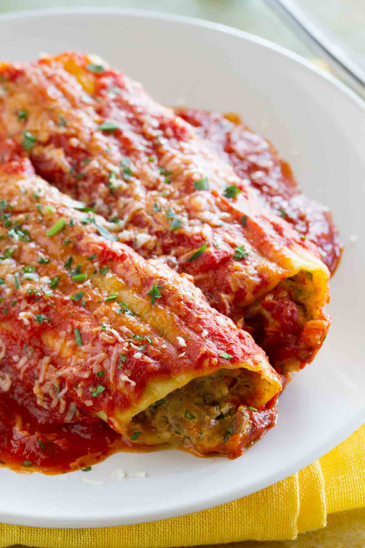 Close up of stuffed manicotti with beef topped with red sauce.
