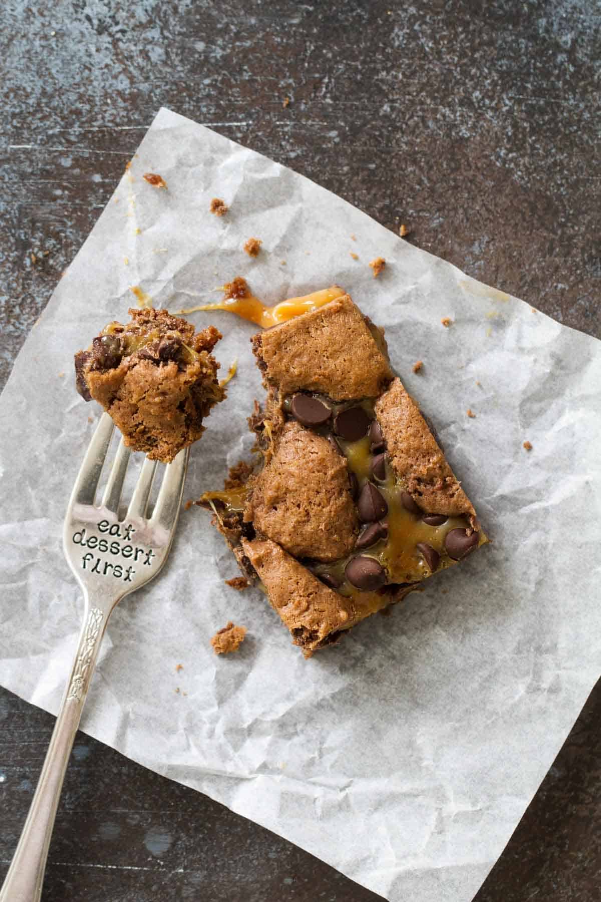 Caramel brownie with a bite taken on a fork that says eat dessert first.