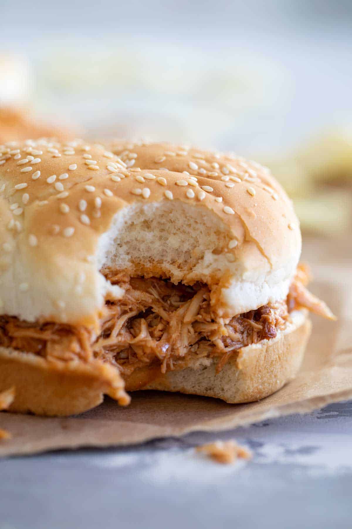 Crockpot BBQ Pulled Chicken Sandwich with a bite taken from it.