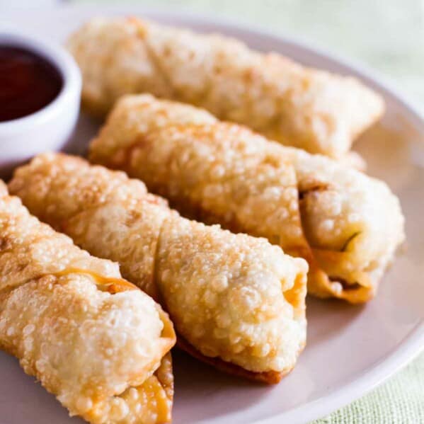 homemade egg rolls on a plate with sweet and sour sauce