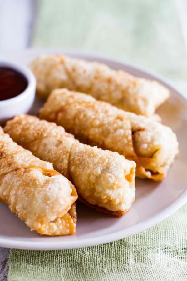homemade egg rolls on a plate with sweet and sour sauce