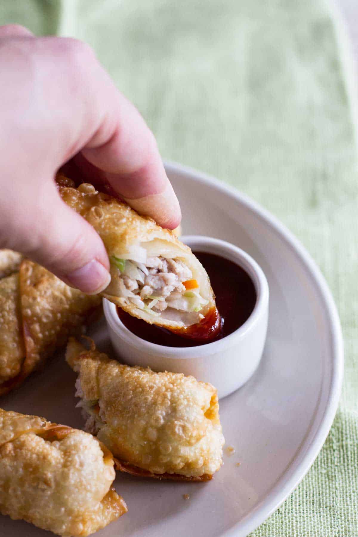 Dipping an egg roll into sweet and sour sauce.