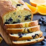 Orange Blueberry Quick Bread cut into slices on a cutting board.