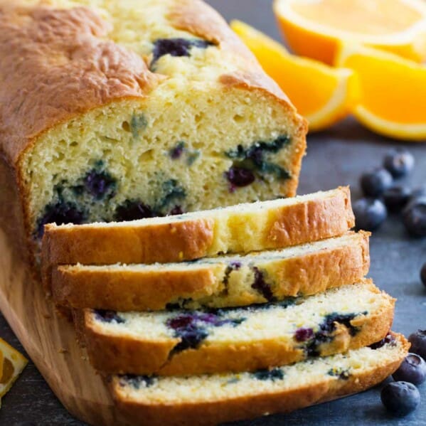 Orange Blueberry Quick Bread cut into slices on a cutting board.