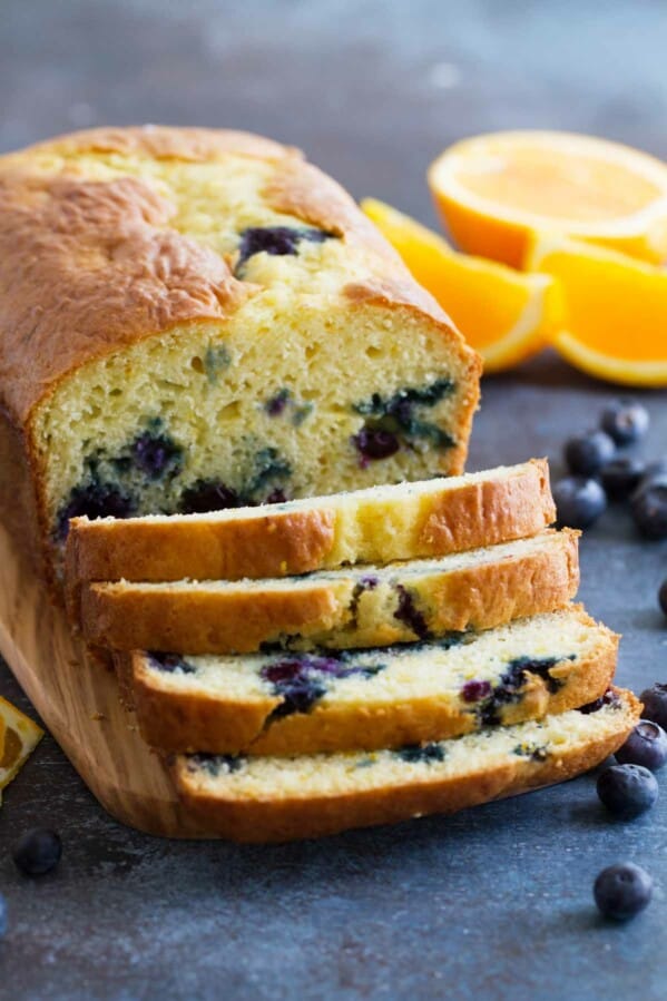 Orange Blueberry Quick Bread cut into slices on a cutting board.