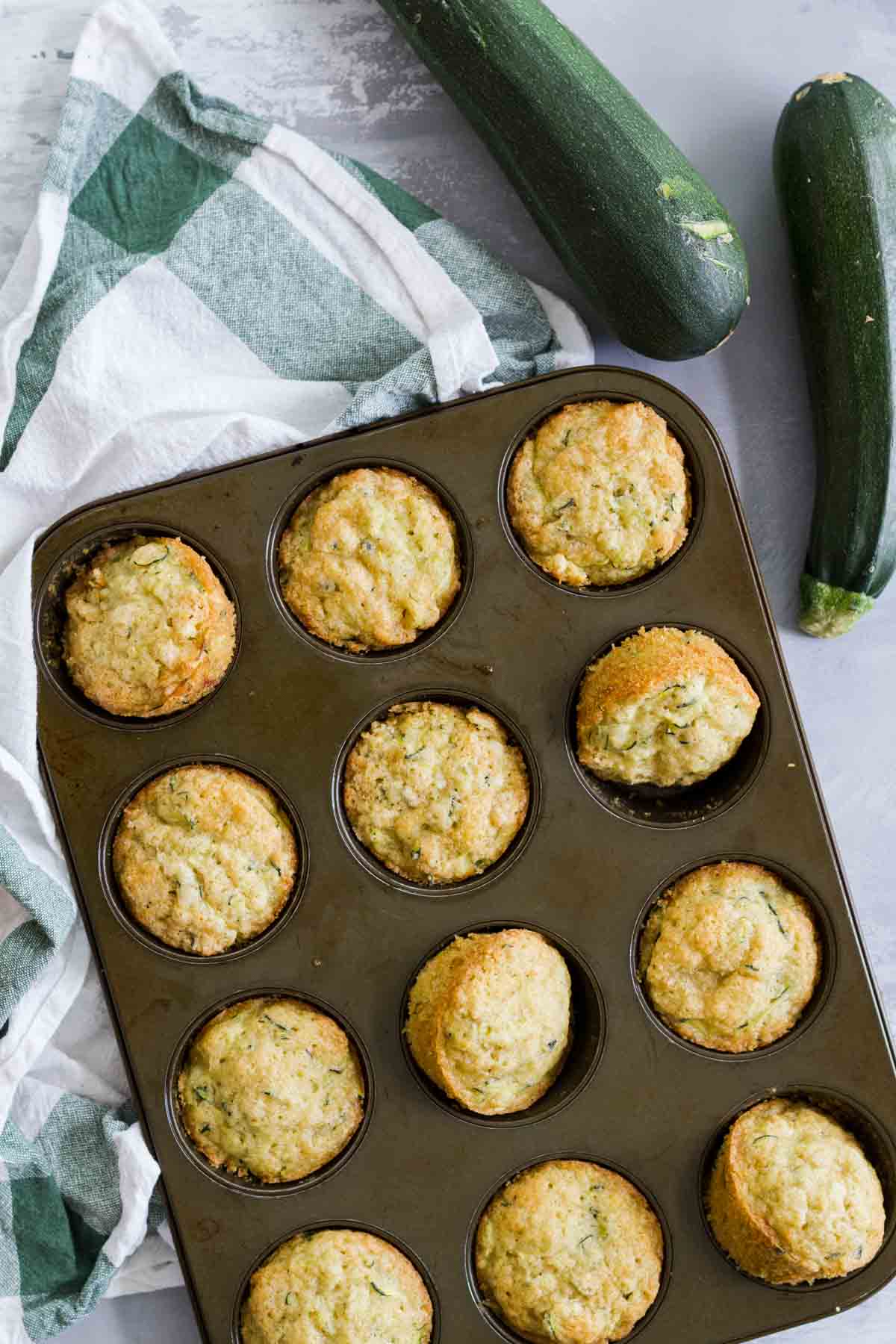overhead view of Zucchini Muffins in a pan with zucchini on the side
