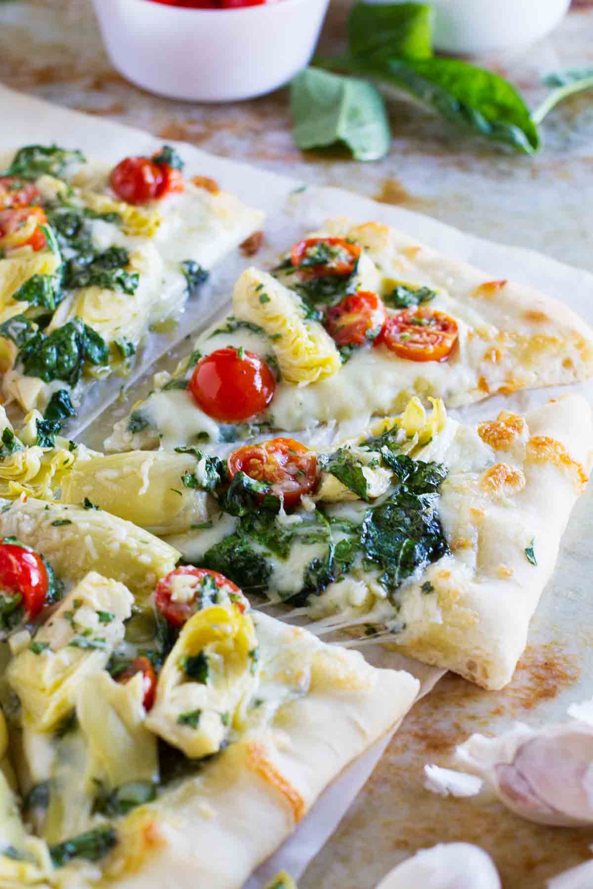 Pizza topped with artichokes, tomatoes and spinach