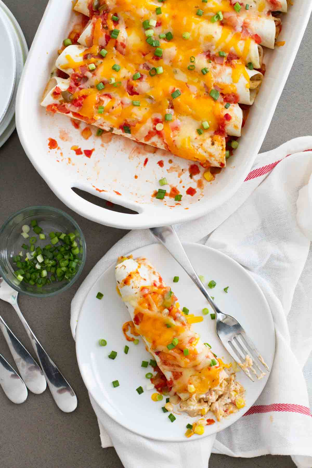 Cream Cheese Chicken Enchiladas on a plate with a dish of enchiladas next to it.