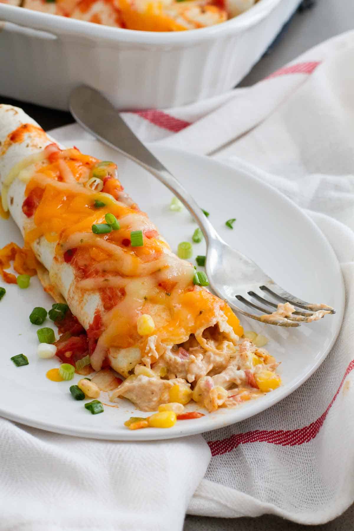 Cream Cheese Chicken Enchiladas cut into with a bite take from it.