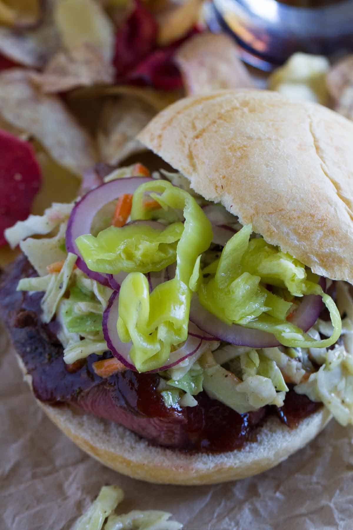 sandwich with sliced steak and coleslaw and peppers for topping.