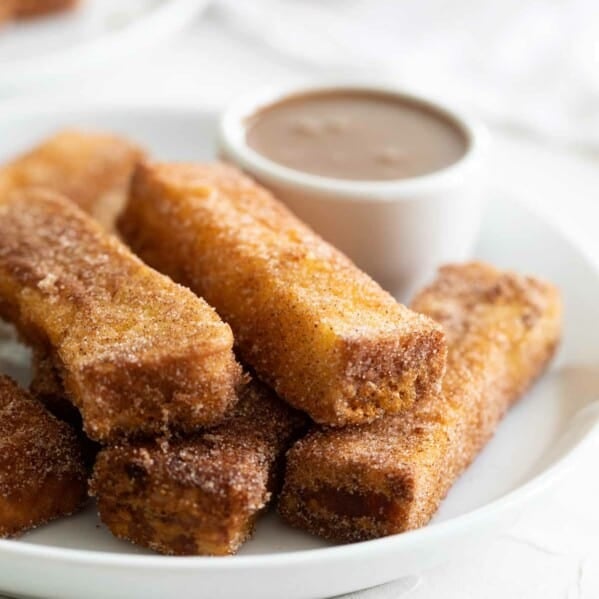 French Toast Sticks with buttermilk syrup in the background for dipping.