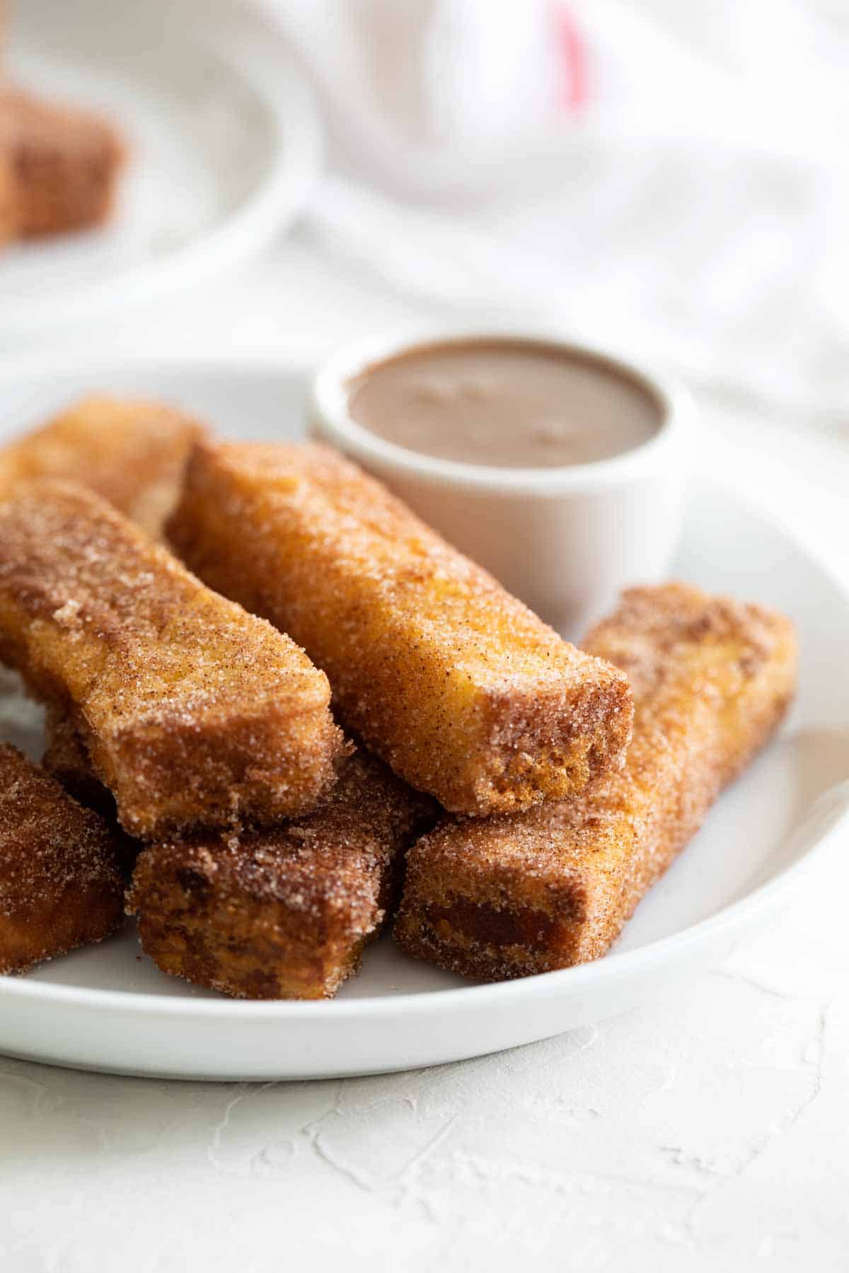 French Toast Sticks with buttermilk syrup in the background for dipping.