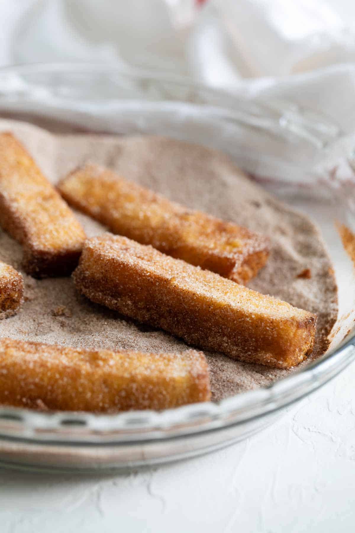 French Toast Sticks being covered in Cinnamon Sugar.