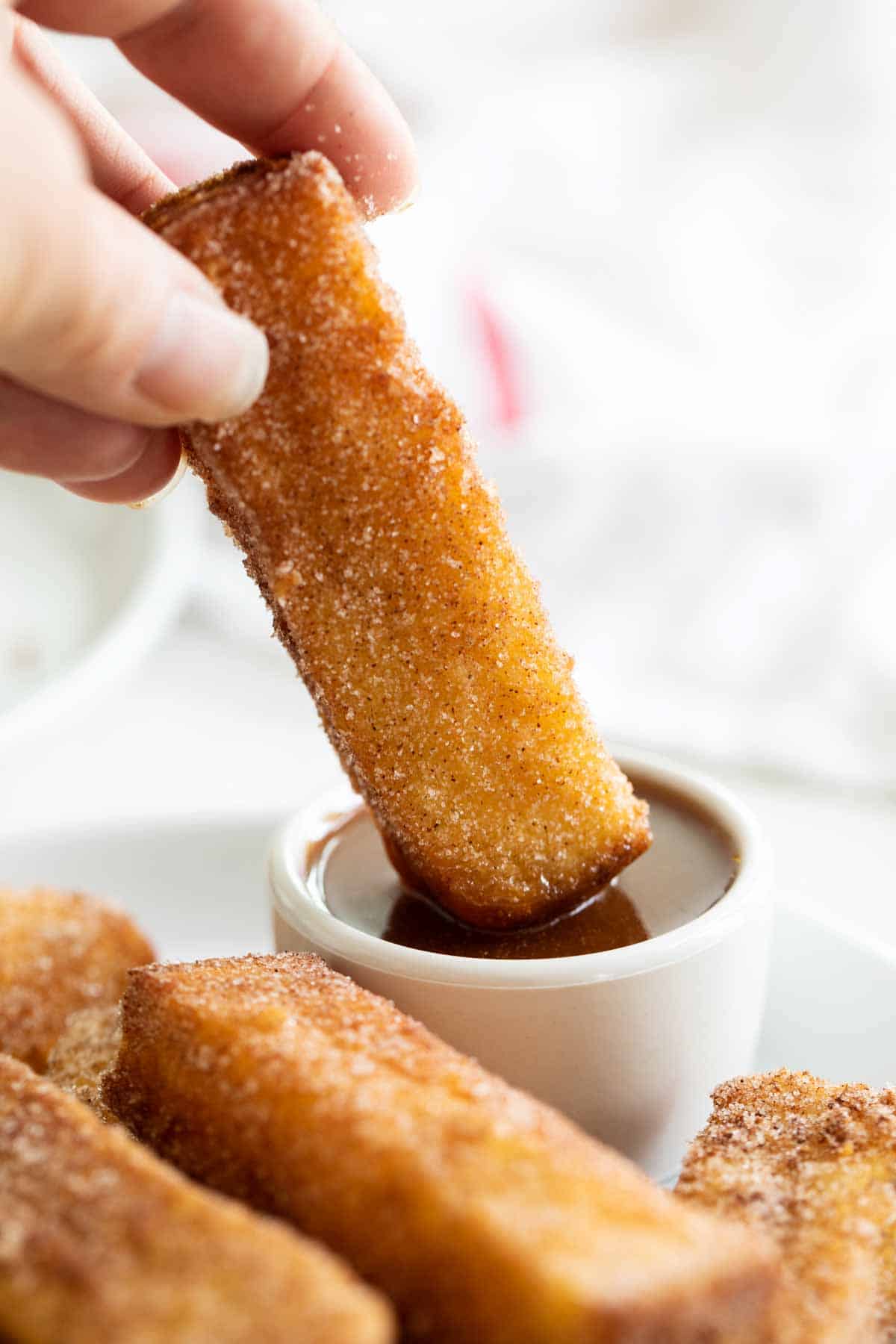 French Toast Sticks being dipped in Buttermilk Syrup.