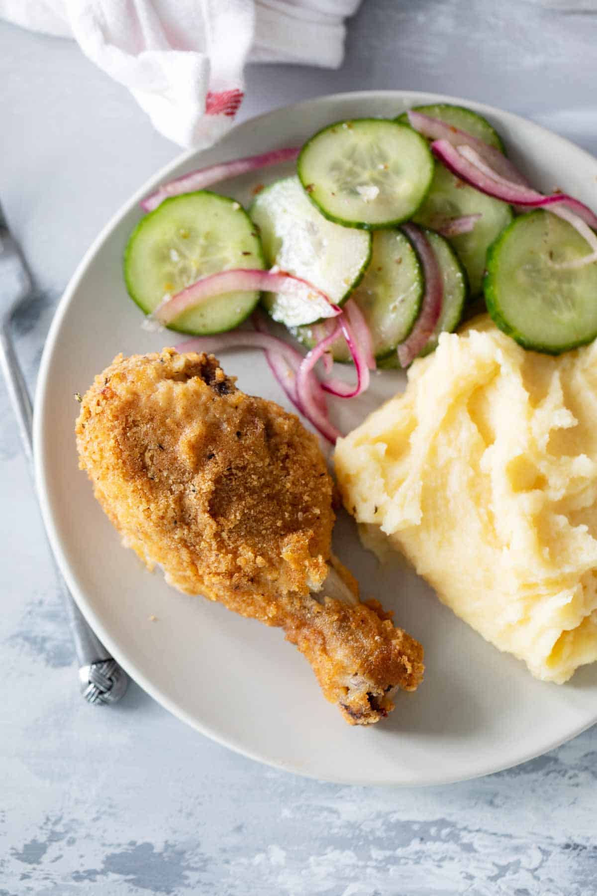 Plate with crispy oven baked chicken drumsticks and salad and potatoes