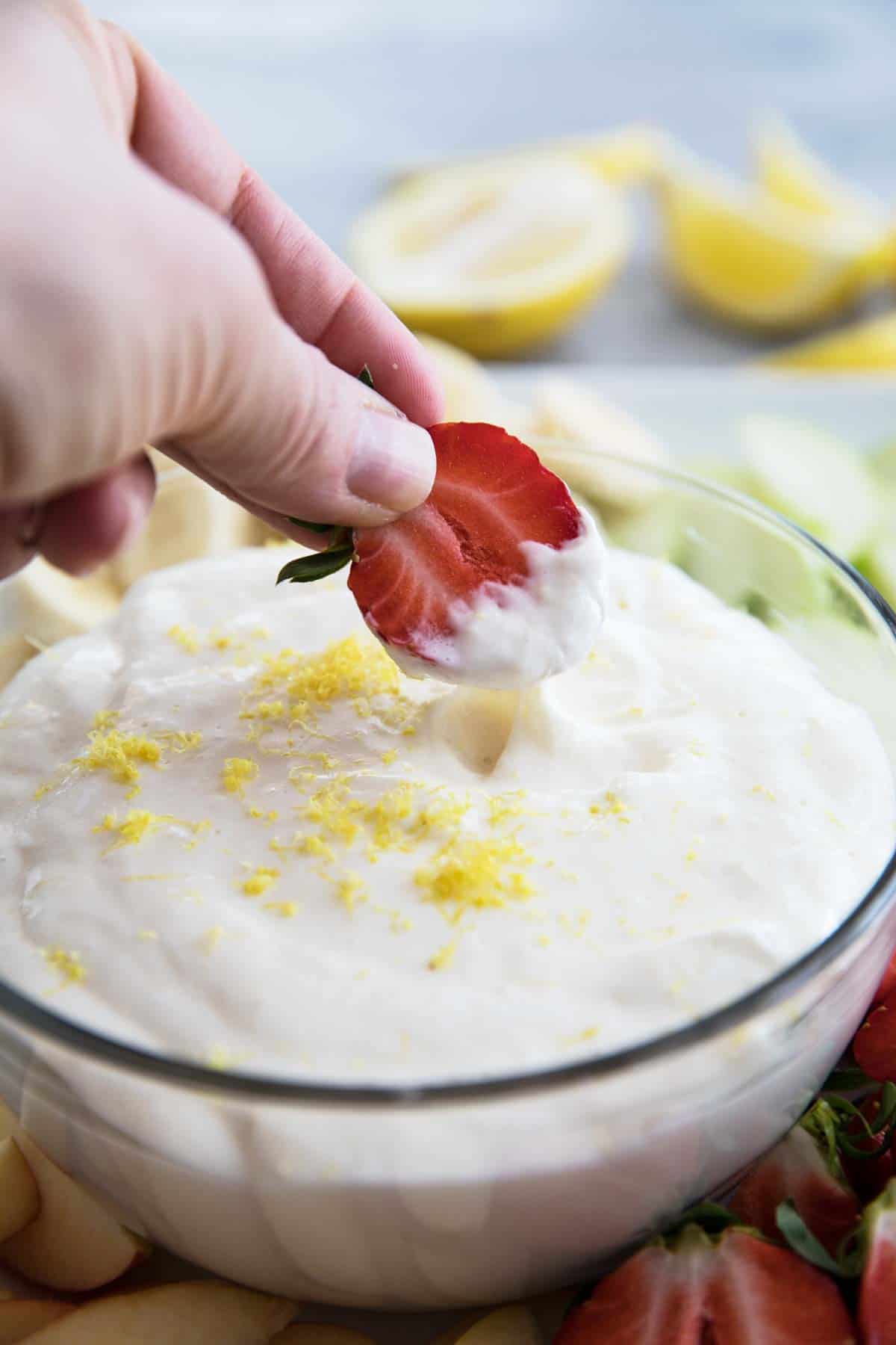 Dipping a strawberry into Lemon Cream Cheese Fruit Dip