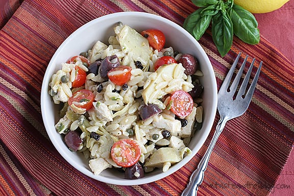 Bowl of Mediterranean Pasta Salad with orzo, tomatoes, artichoke hearts, and more.