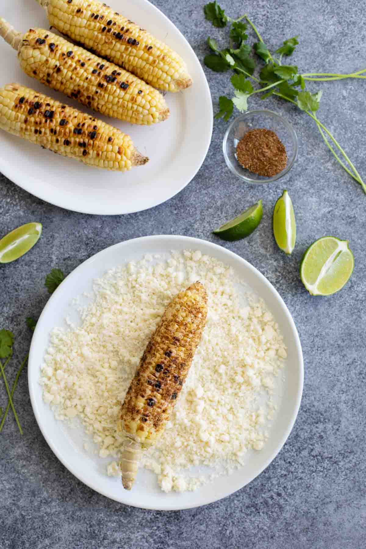 rolling grilled corn in cotija cheese