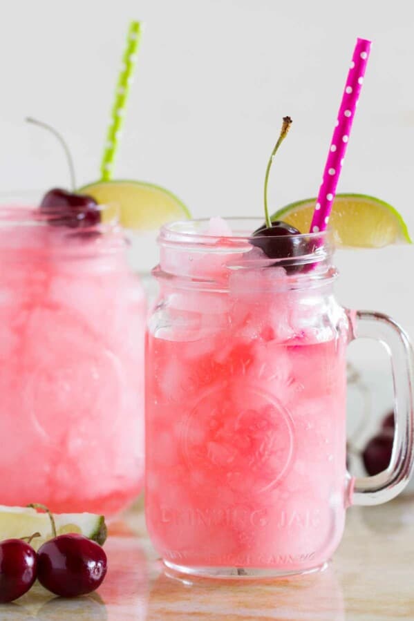 homemade slurpees in glasses with lime slices, cherries and straws