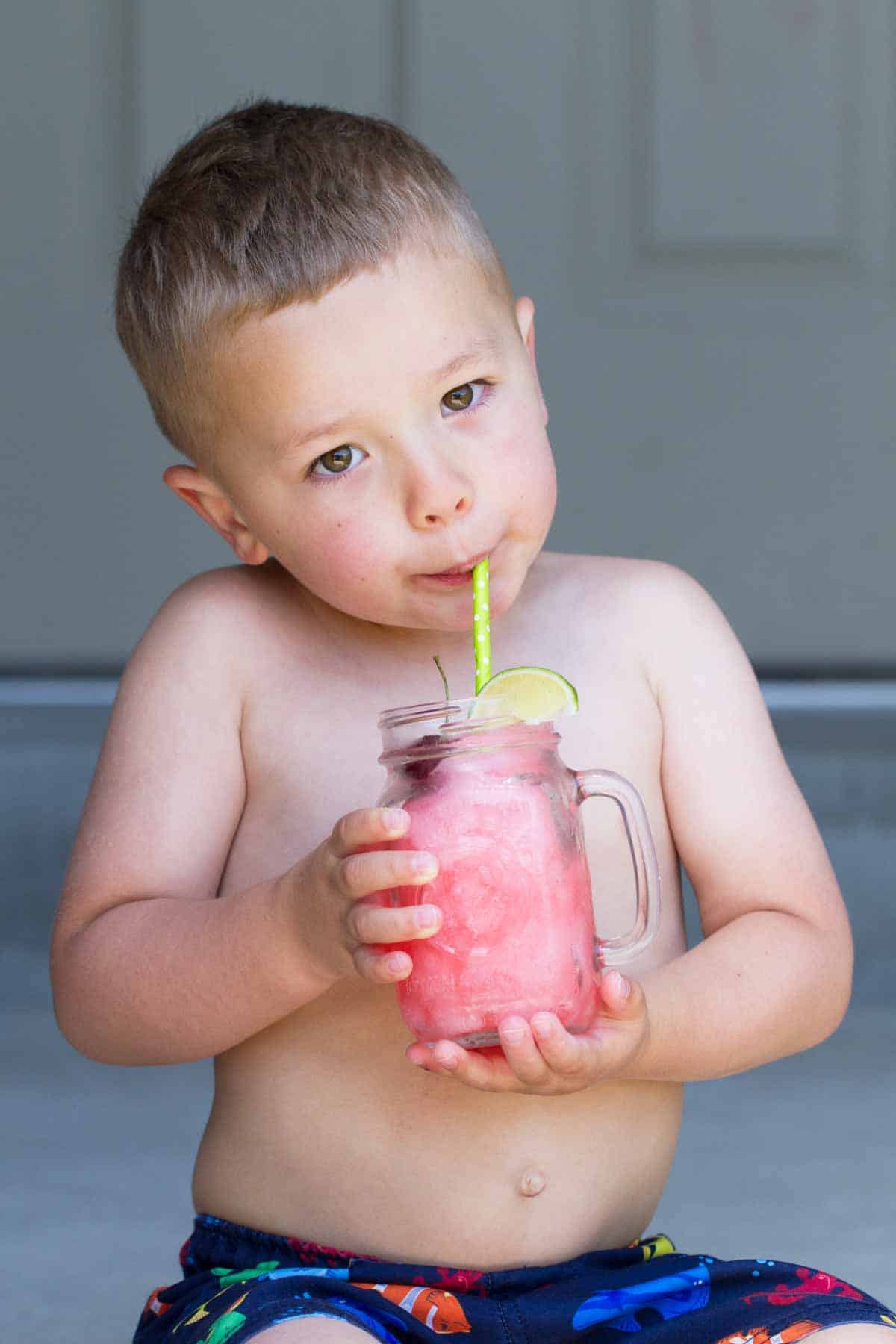 Boy drinking from a glass filled with homemade slurped.