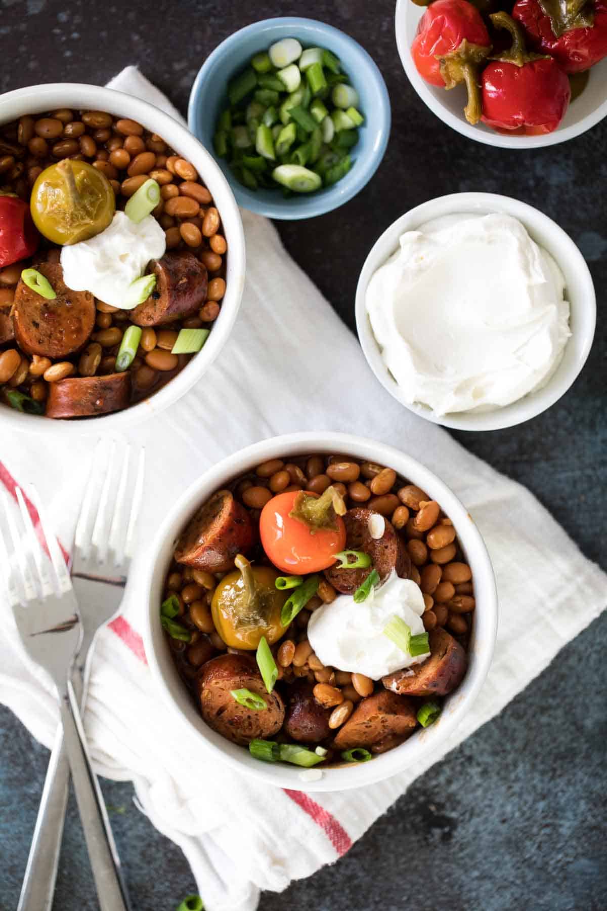 Crock Pot Beans and Sausage in bowls, topped with cherry peppers and onions.