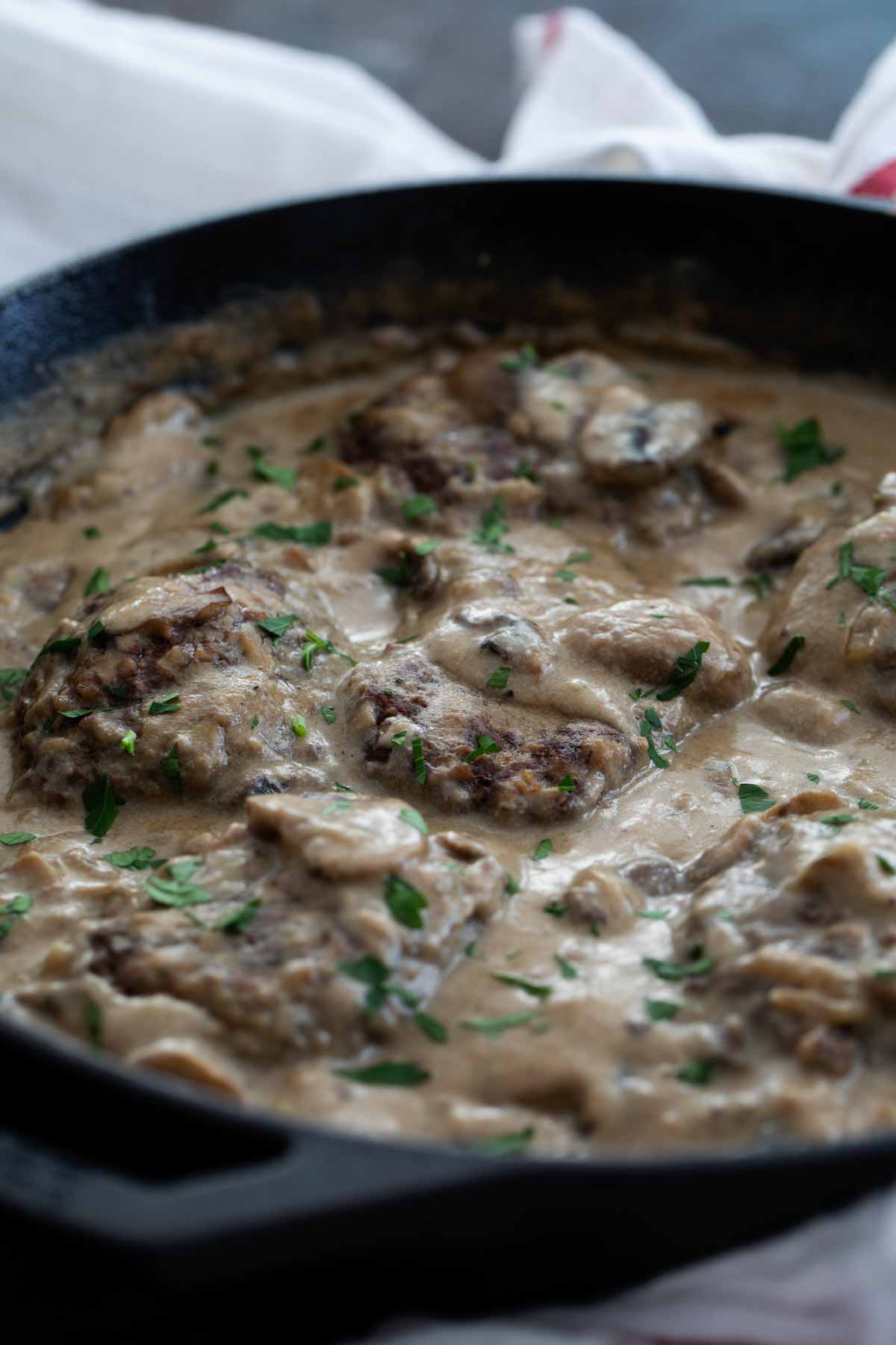 Salisbury Steak in a cast iron pan with gravy.