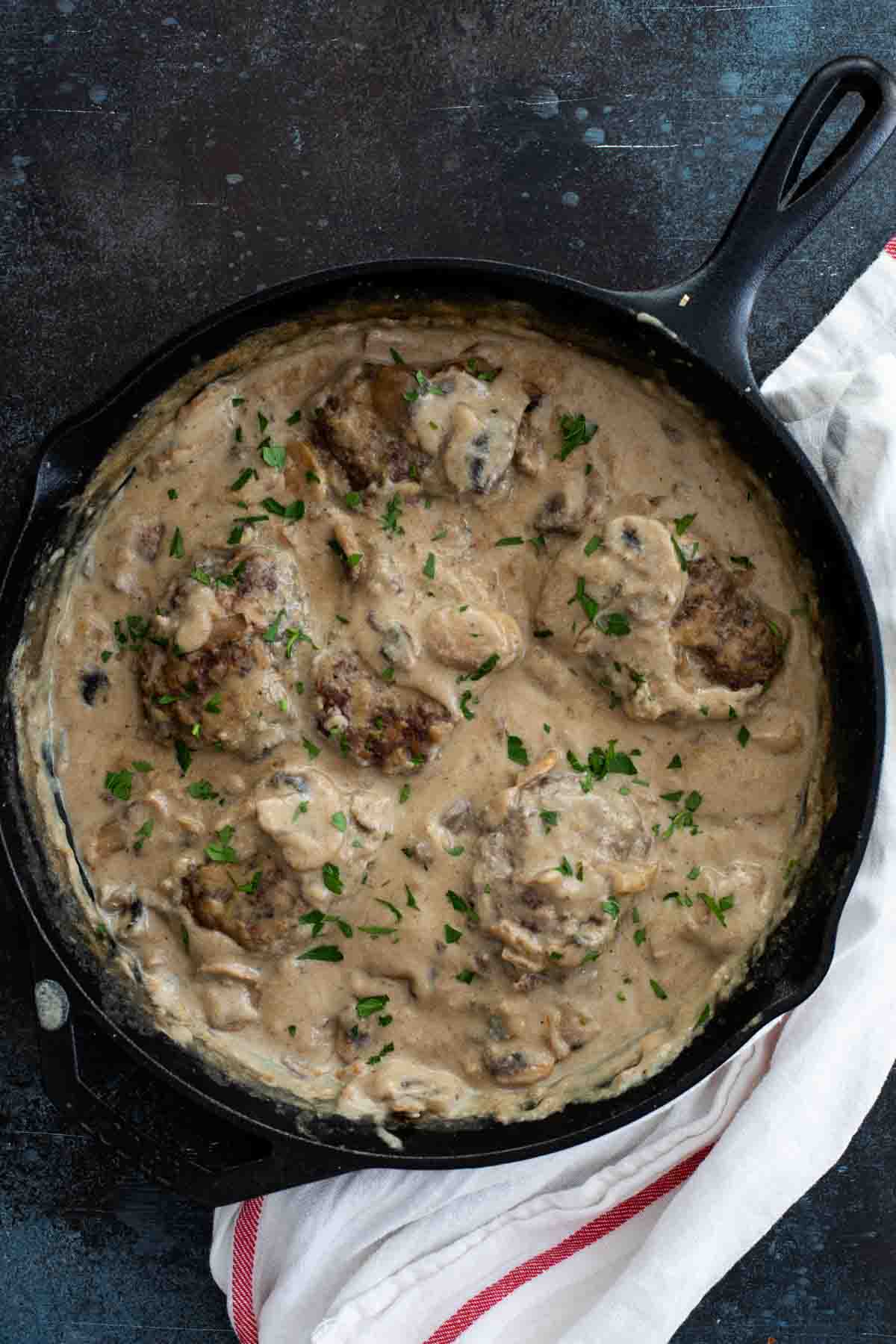 Salisbury steak with gravy in a cast iron pan.