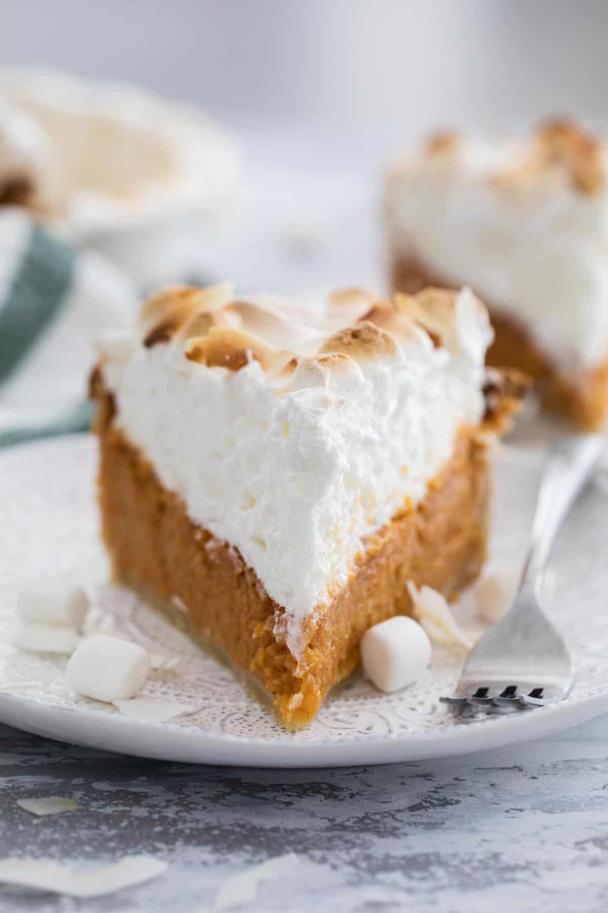 slice of sweet potato pie with tall meringue on a plate with a fork