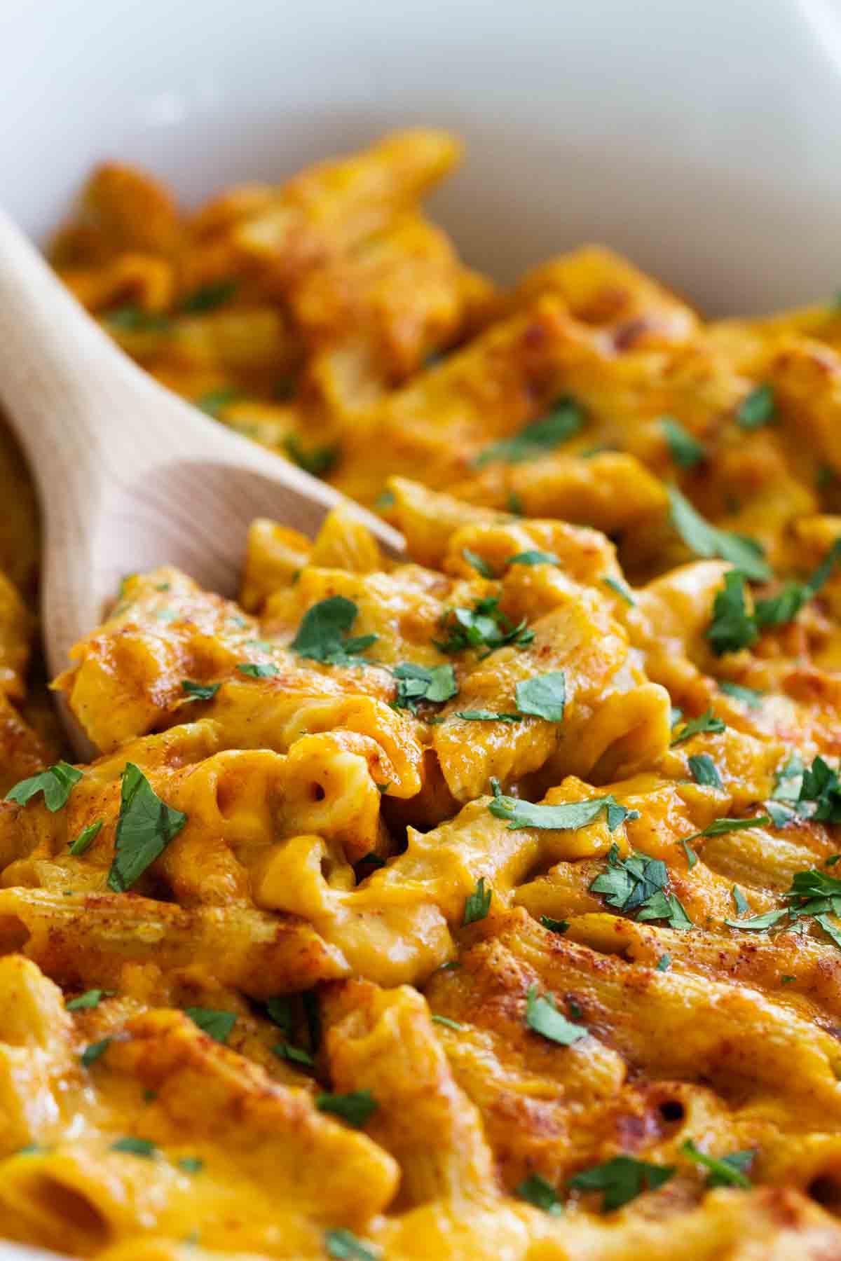 Dish of pumpkin cheddar mac and cheese with a wooden spoon.