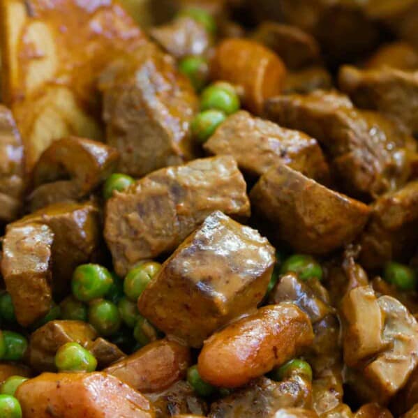 Chili beef and vegetables in a pot with a wooden spoon.