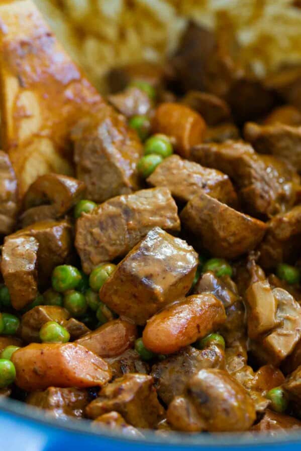 Chili beef and vegetables in a pot with a wooden spoon.