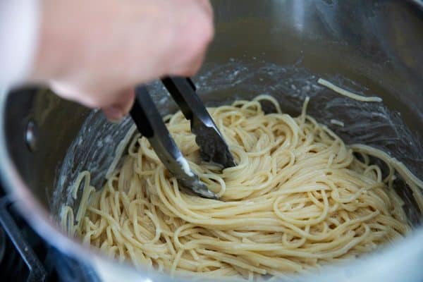 Mixing pasta and ingredients in a large pot.