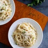 Bowls of parmesan pasta topped with cheese and herbs.