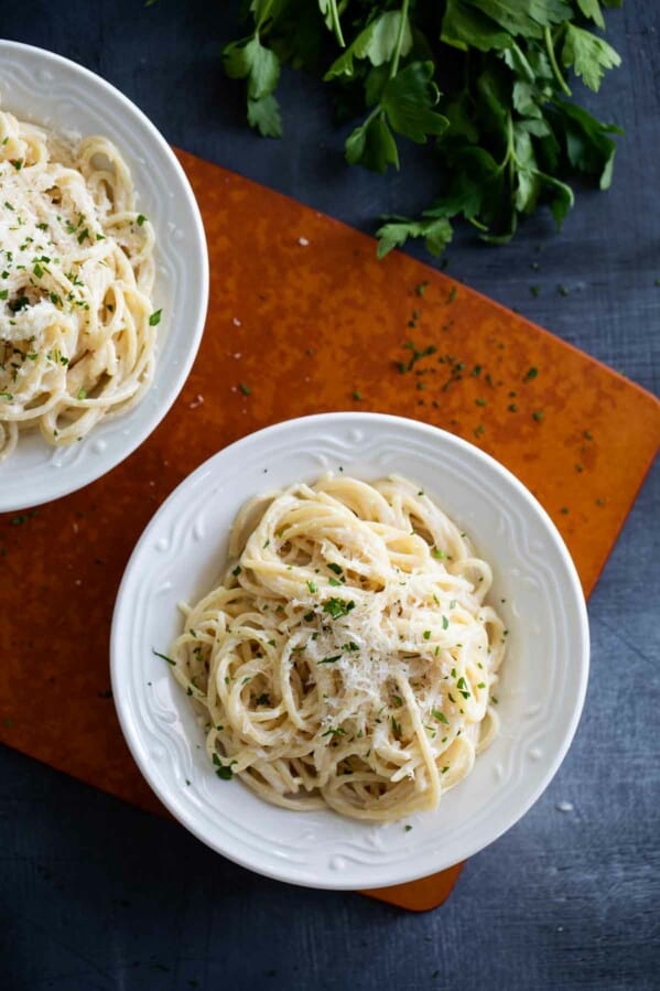 Bowls of parmesan pasta topped with cheese and herbs.