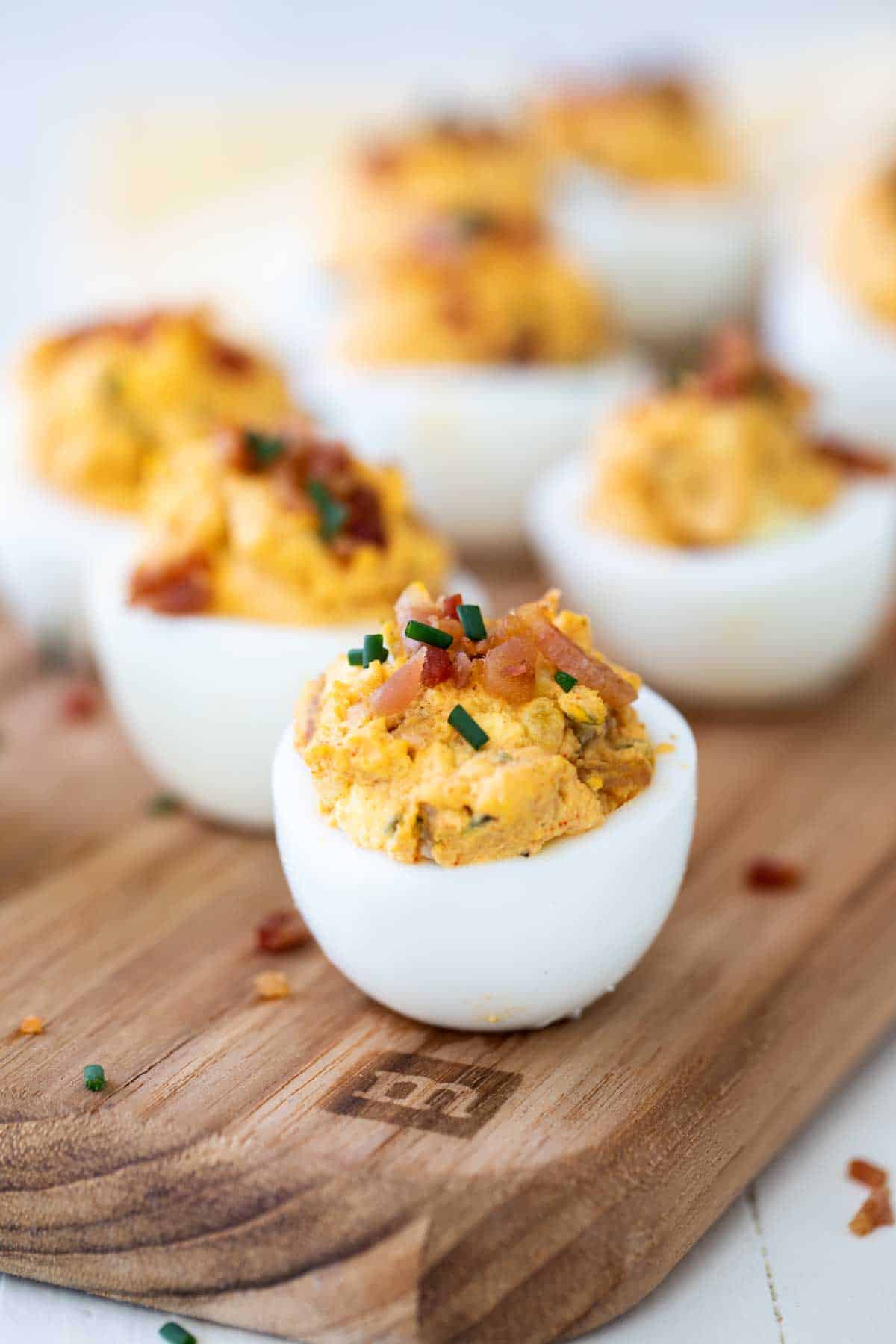 Bacon Deviled Eggs topped with pieces of bacon and chives.